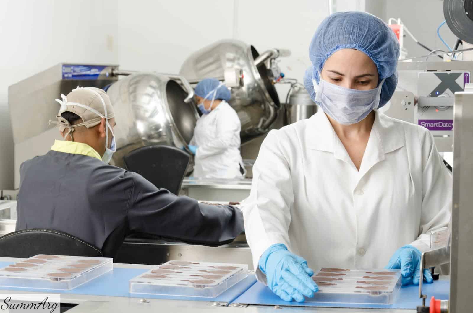 three people inside factory wearing masks and coats