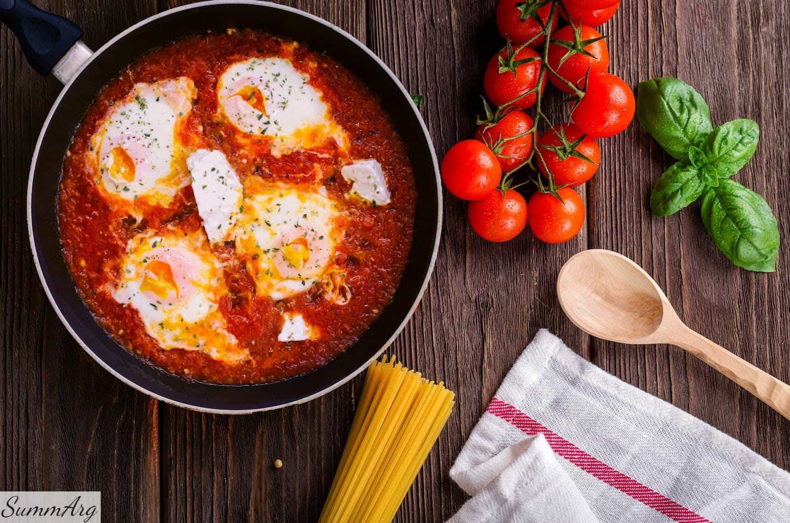 Black Frying Pan With Spaghetti Sauce Near Brown Wooden Ladle and Ripe Tomatoes