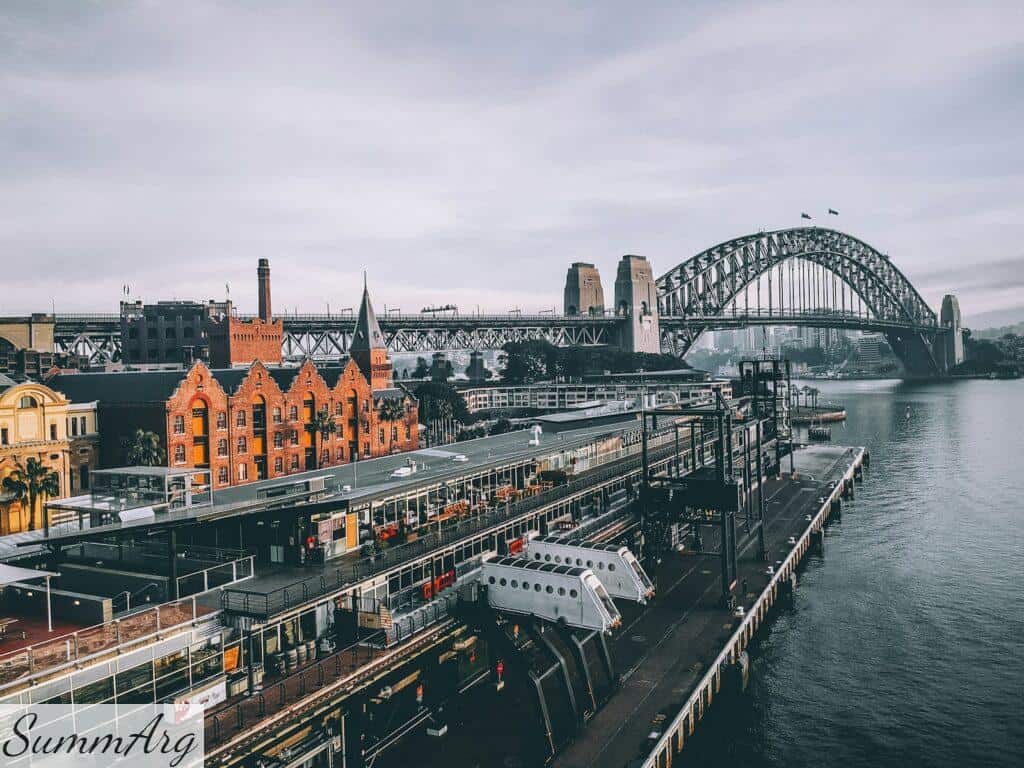 aerial photography of concrete buildings and bridge beside ocean under cloudy sky