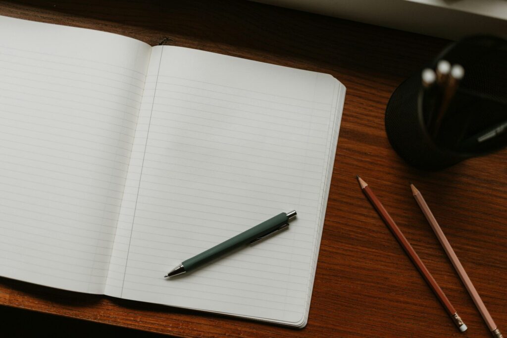 Cuaderno abierto con bolígrafo y lápices sobre un escritorio